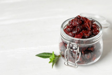 Photo of Tasty dried cranberries and leaves on white table. Space for text