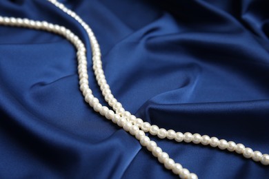 Photo of Beautiful pearls on delicate dark blue silk