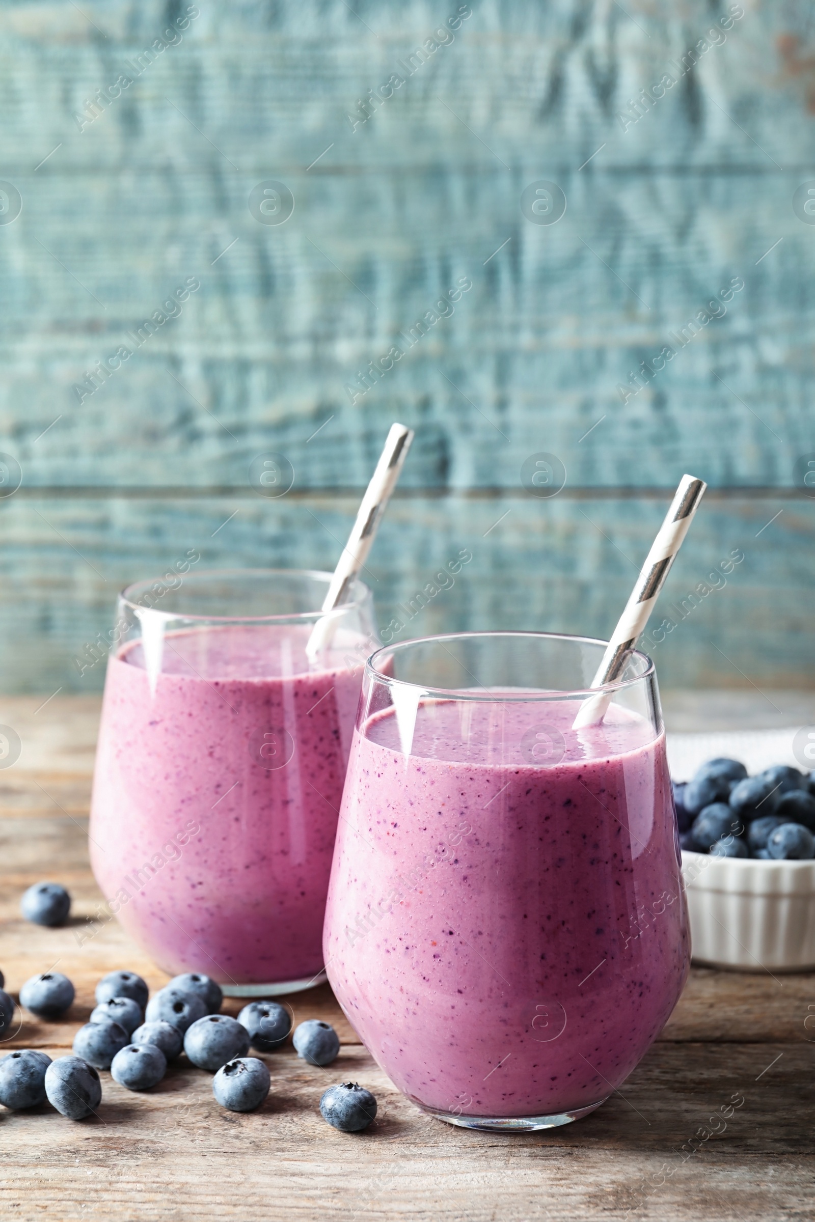 Photo of Tasty blueberry smoothie in glasses and berries on wooden table