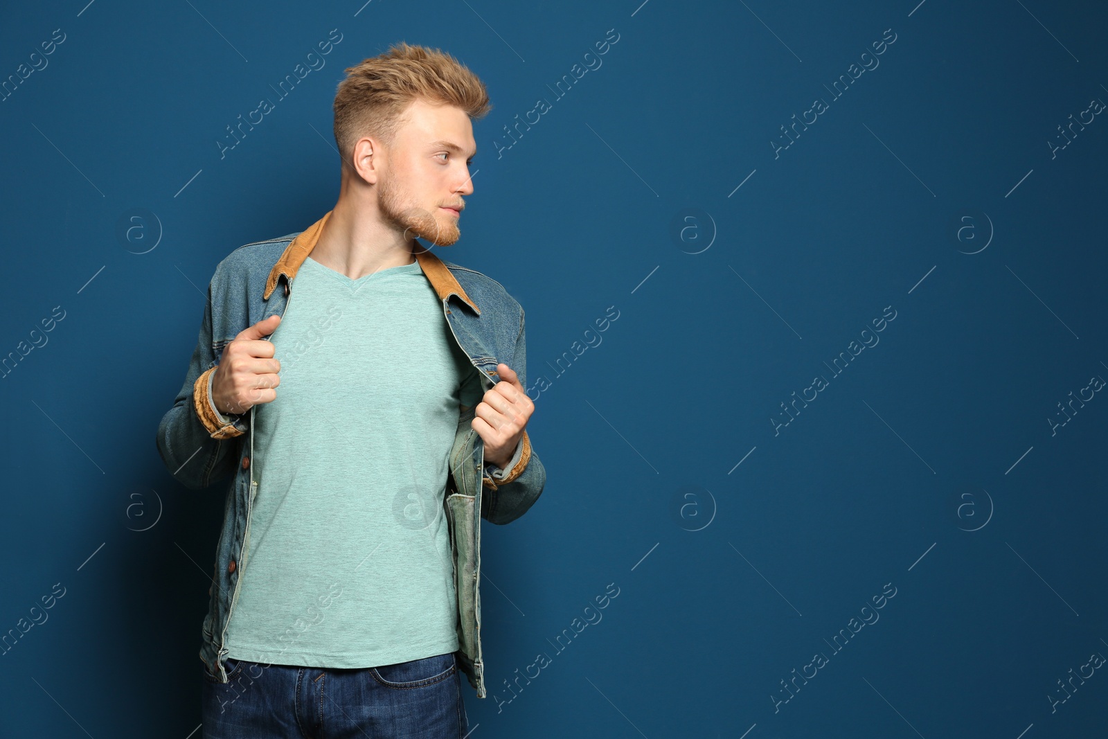 Photo of Young man wearing blank t-shirt on blue background. Mockup for design