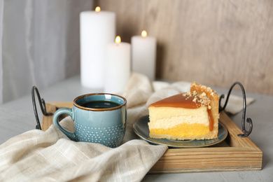 Cup of tea and delicious cheesecake on grey table
