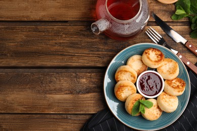 Delicious cottage cheese pancakes with jam on wooden table, flat lay. Space for text