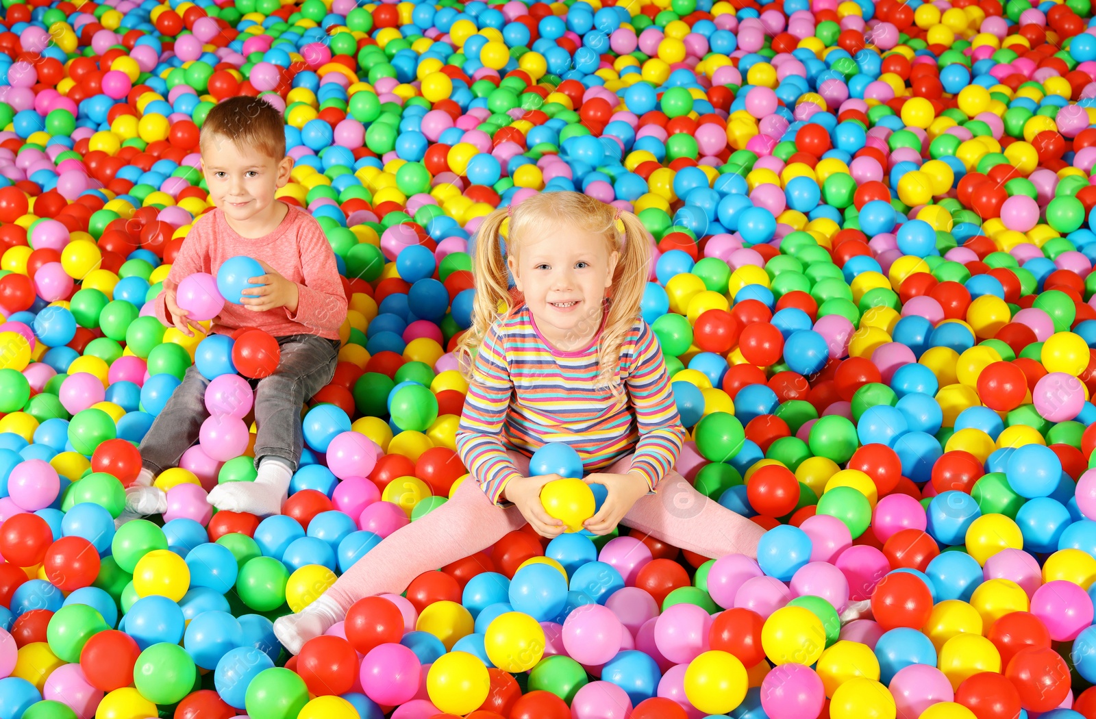 Photo of Cute children playing in ball pit indoors