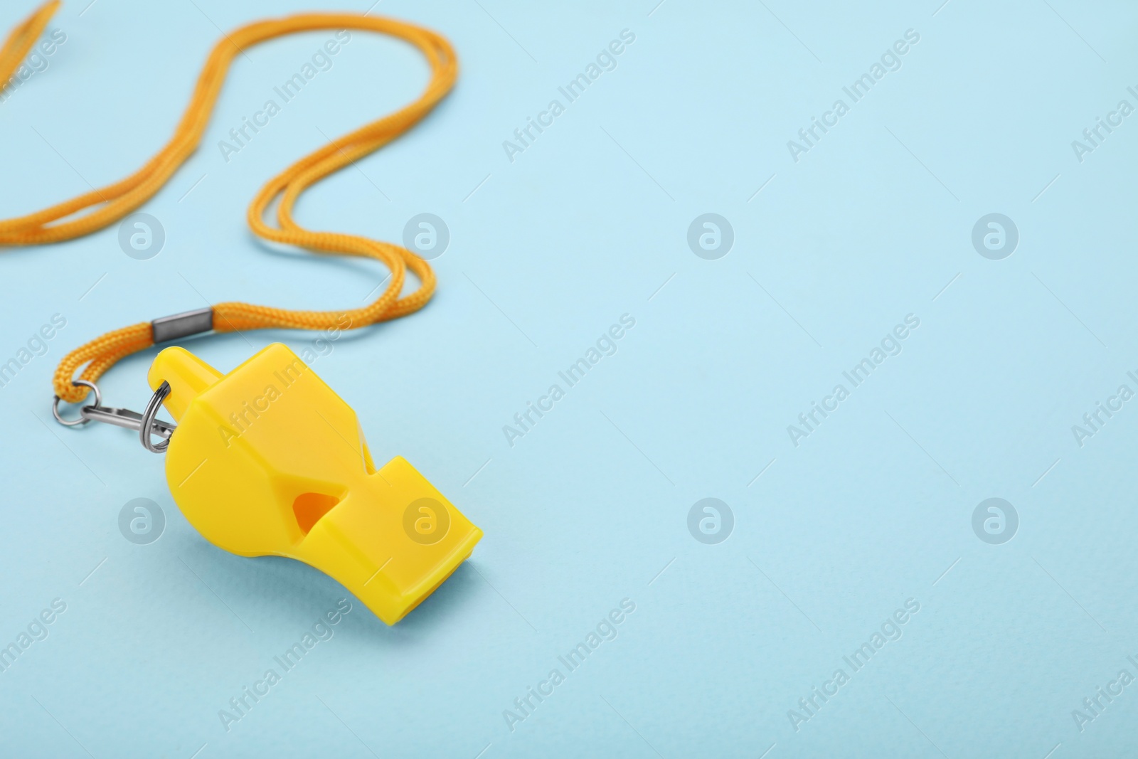 Photo of One yellow whistle with cord on light blue background. Space for text