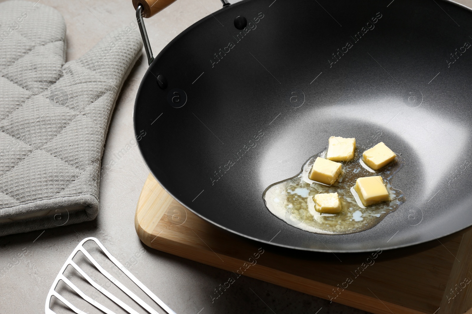 Photo of Frying pan with melting butter on grey table, closeup