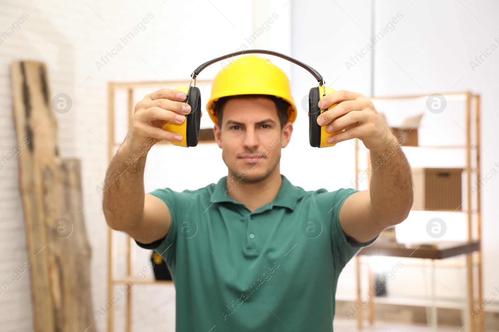 Photo of Worker holding safety headphones indoors, focus on hands. Hearing protection device