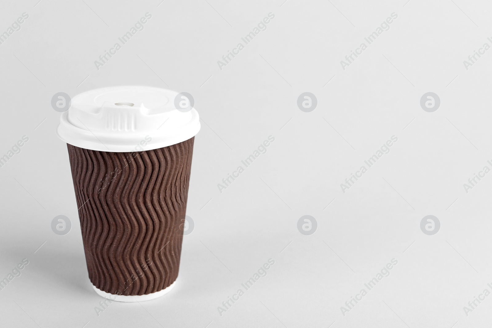 Photo of Brown paper cup with plastic lid on light background, space for text. Coffee to go