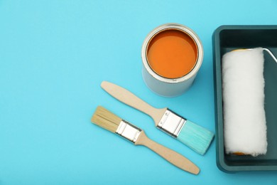 Can of orange paint, brushes, roller and container on turquoise background, flat lay. Space for text
