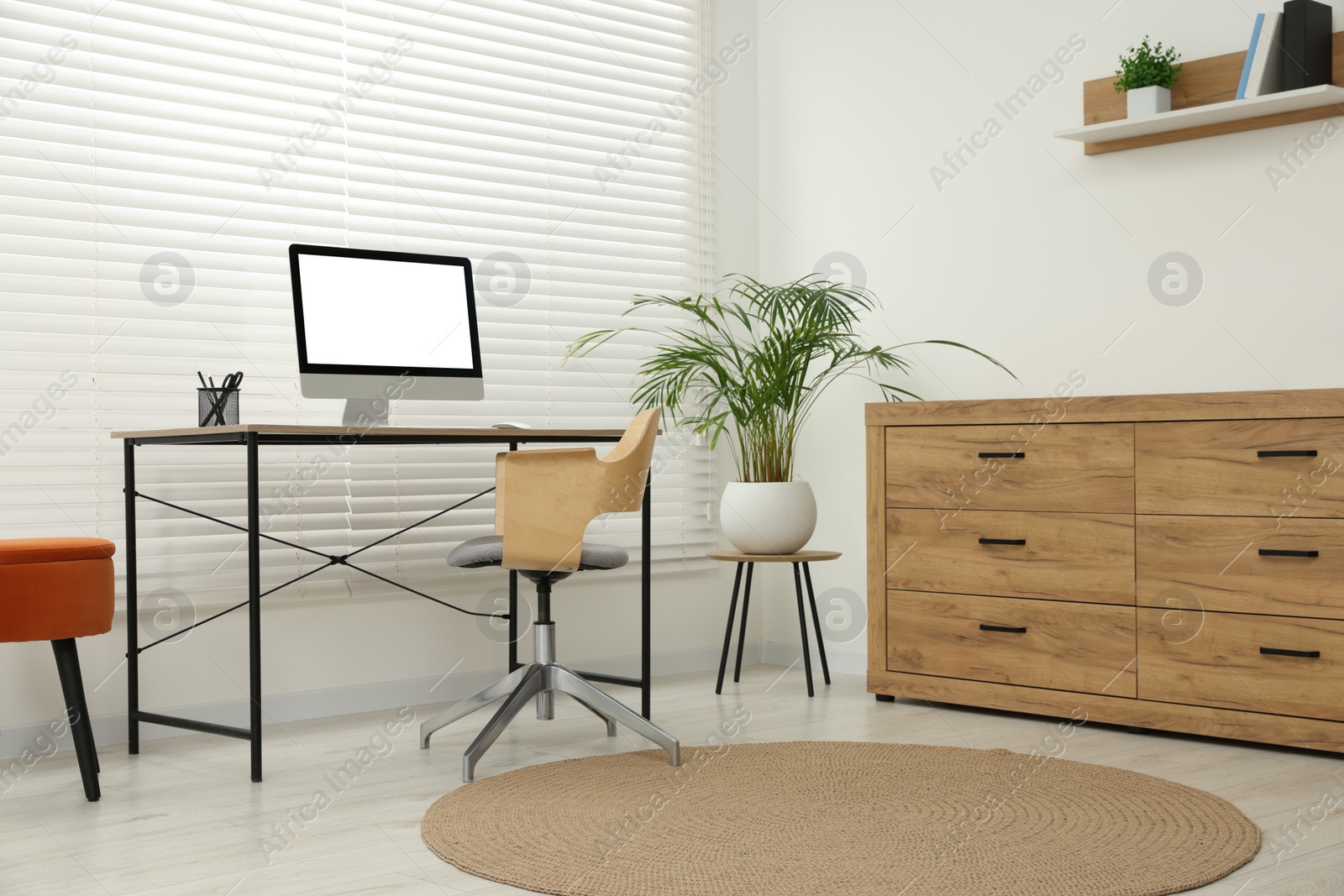 Photo of Stylish office interior with comfortable chair, desk, computer and houseplant