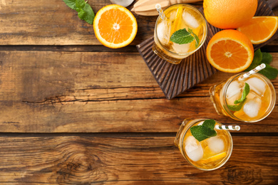 Delicious refreshing drink with orange slices on wooden table, flat lay. Space for text