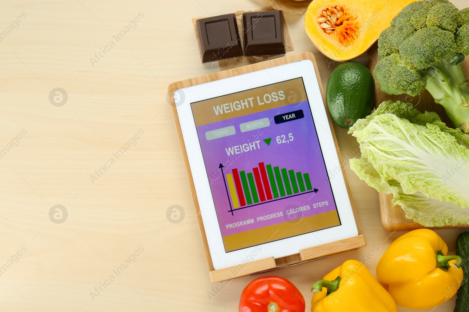 Photo of Tablet with weight loss calculator application and food products on wooden table, flat lay. Space for text