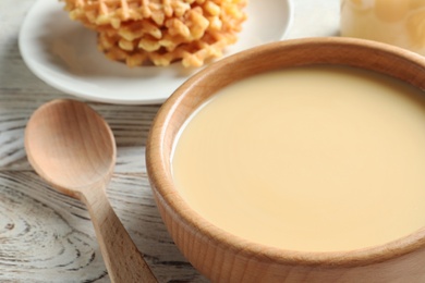 Photo of Bowl with condensed milk served on table, closeup. Dairy products