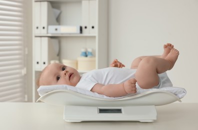 Photo of Cute little baby lying on scales in clinic