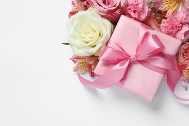 Photo of Gift box and beautiful flowers on white background, flat lay. Space for text