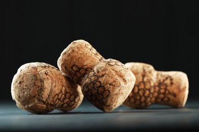 Photo of Corks of wine bottles with grape images on black table, closeup