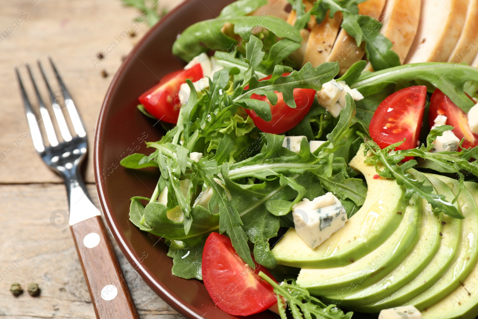 Photo of Delicious salad with chicken, arugula and avocado on table, closeup