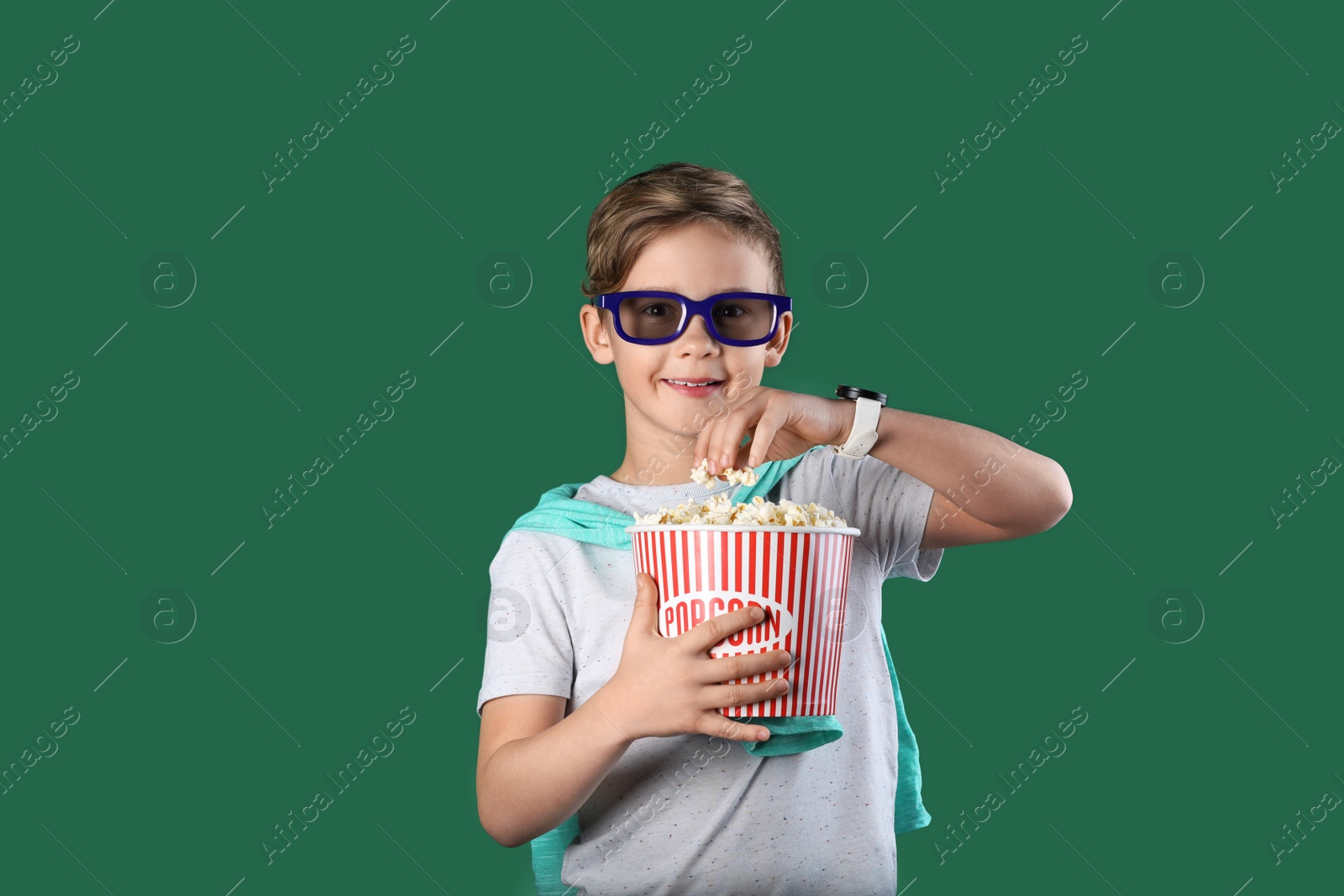 Photo of Cute boy in 3D glasses with popcorn bucket on color background