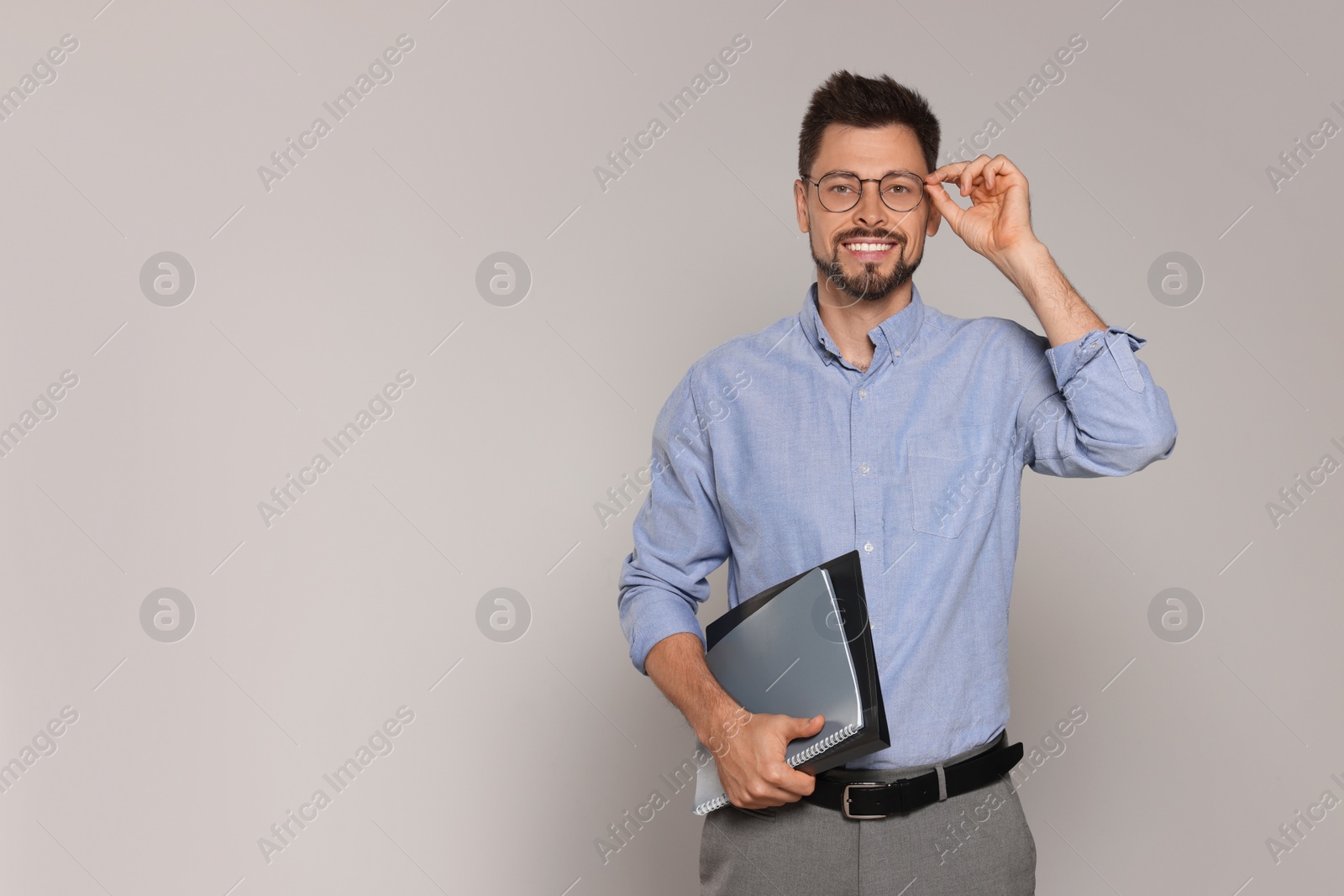 Photo of Happy teacher with glasses and stationery against beige background. Space for text