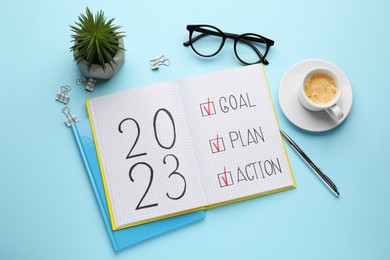 Photo of Flat lay composition of notebook with text 2023 Goal, Plan, Action on light blue background. New Year aims