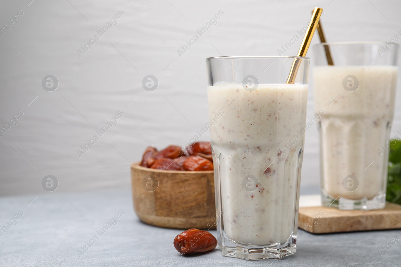 Photo of Glasses of delicious date smoothie and dried fruits on light grey table. Space for text
