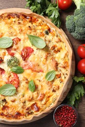 Photo of Tasty cheese quiche and ingredients on wooden table, flat lay