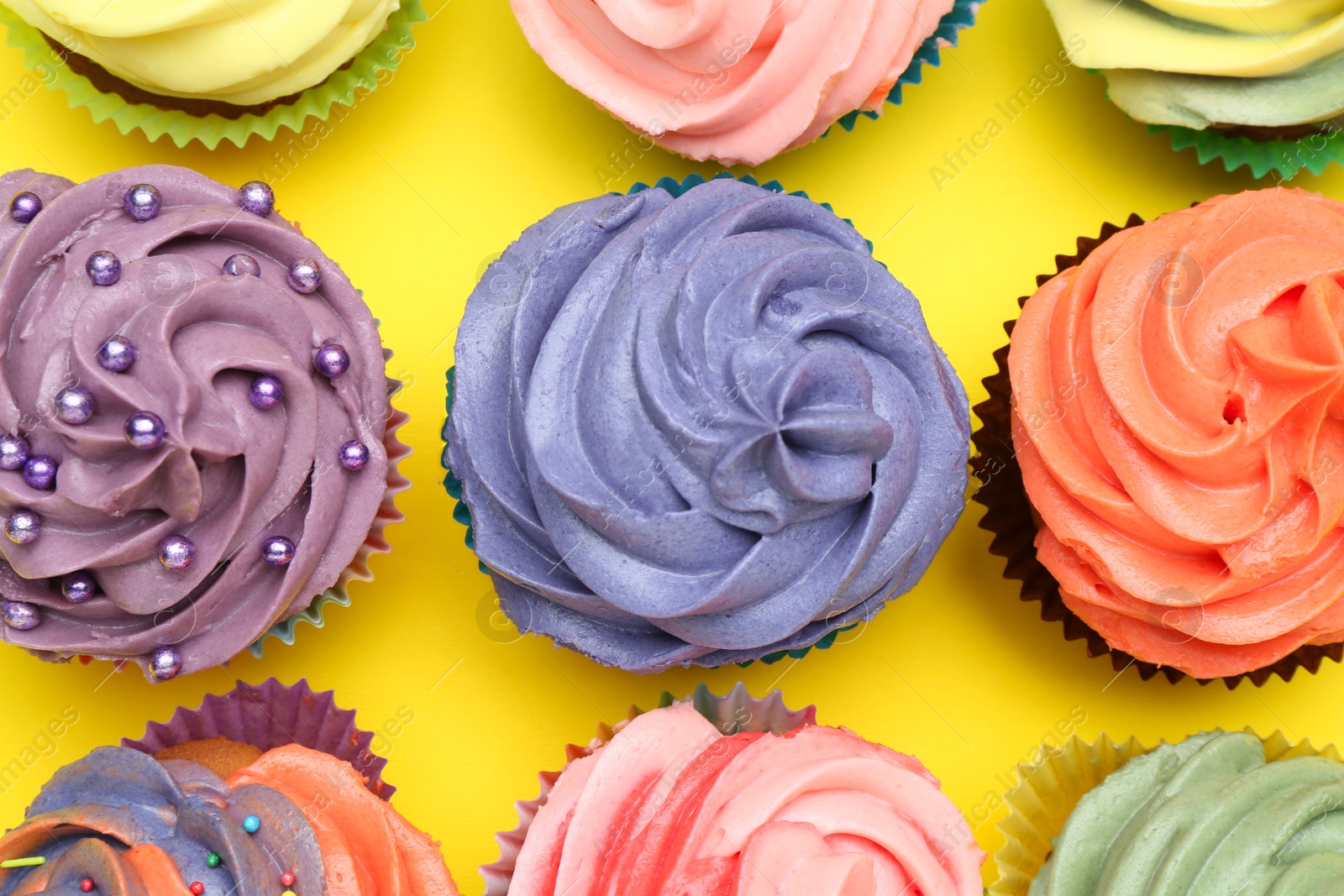 Photo of Delicious cupcake with bright cream on yellow background, flat lay