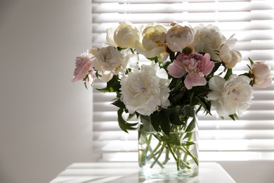 Photo of Beautiful peonies in vase on table near window indoors