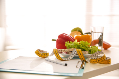 Photo of Composition with healthy products and measuring tape on table indoors. Diet plan from professional nutritionist