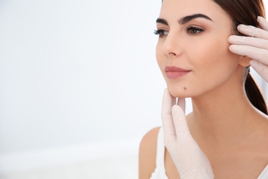 Dermatologist examining young patient's birthmark in clinic. Space for text