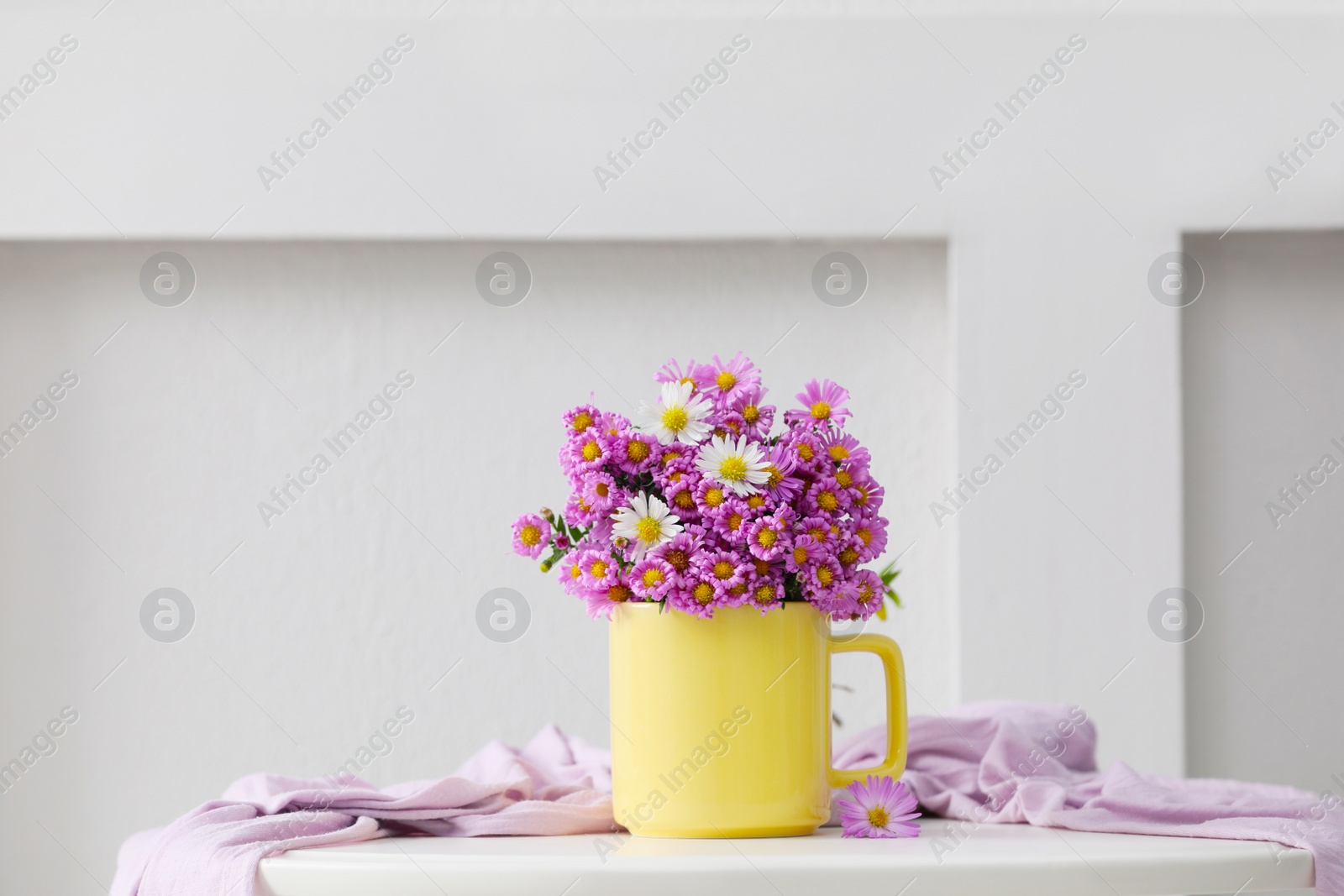 Photo of Cup with beautiful flowers and cloth on white table