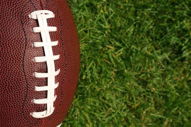 Photo of Top view of American football ball on green field grass, closeup. Space for text