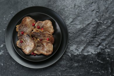Photo of Tasty beef tongue pieces on black textured table, top view. Space for text