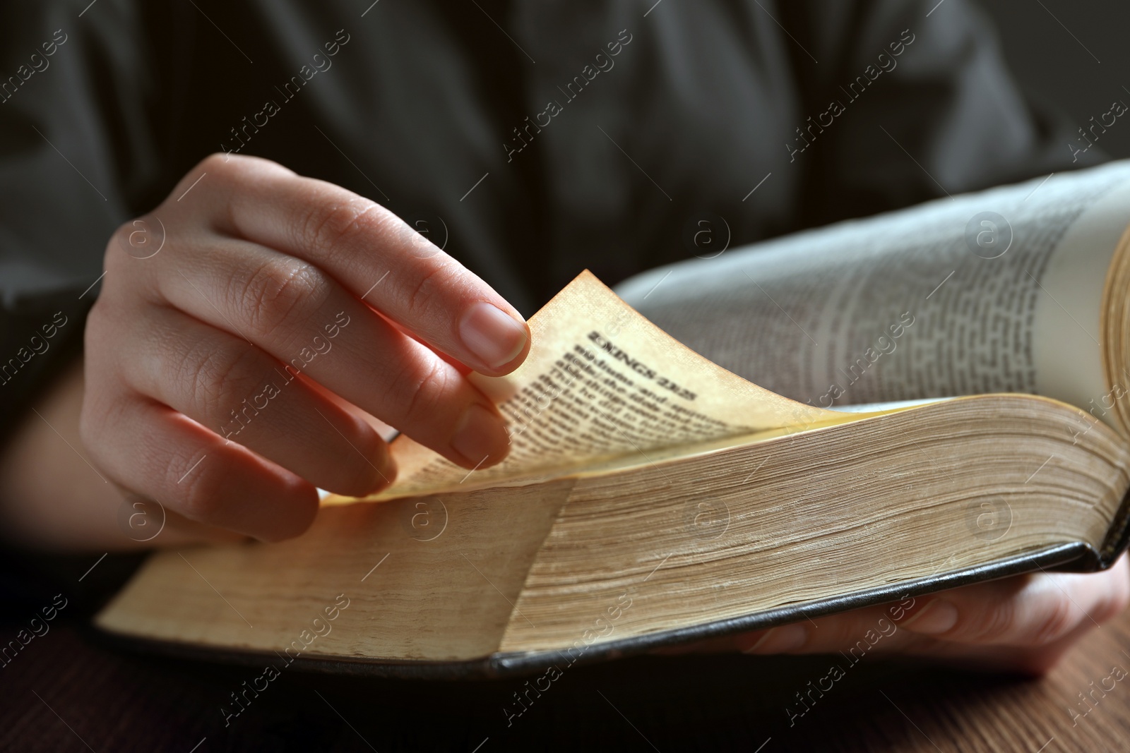 Photo of Woman reading Bible at wooden table, closeup