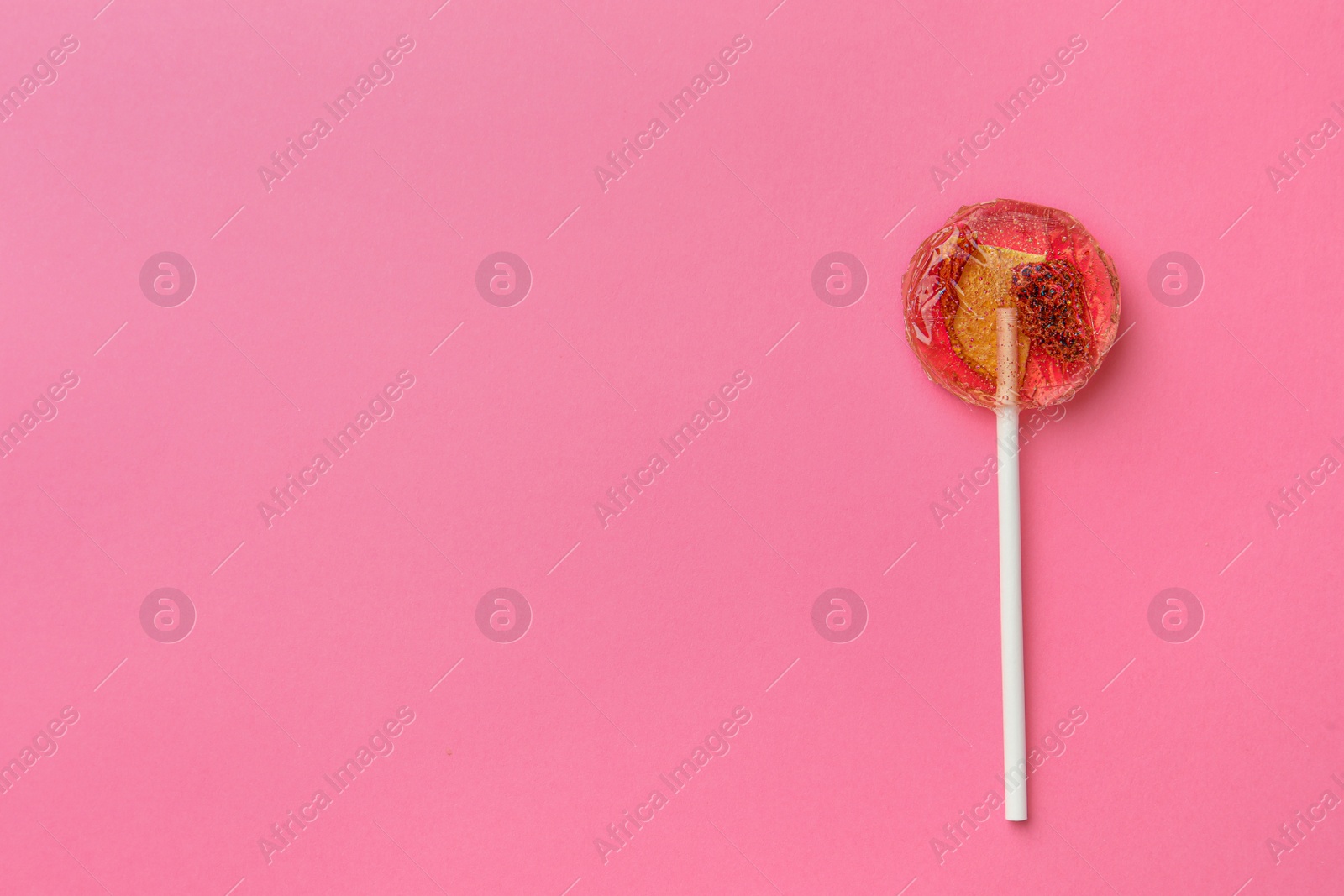 Photo of Sweet colorful lollipop with berries on pink background, top view. Space for text