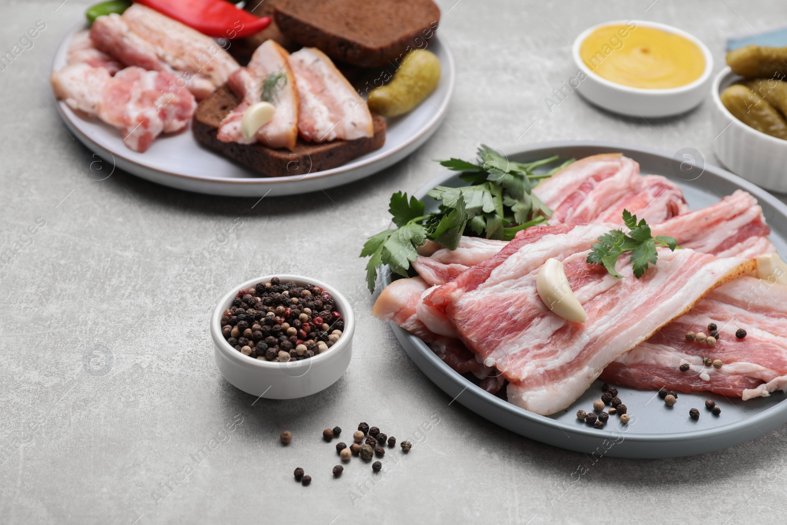 Photo of Slices of tasty pork fatback with spices on grey table