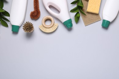 Flat lay composition with different cleaning supplies on light gray background, space for text