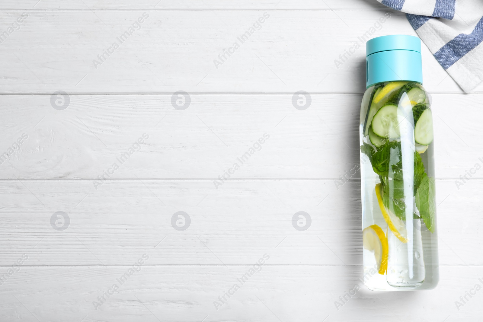 Photo of Bottle of refreshing water with cucumber, lemon and mint on white wooden table, top view. Space for text