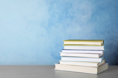 Photo of Stack of hardcover books on table against color background, space for text