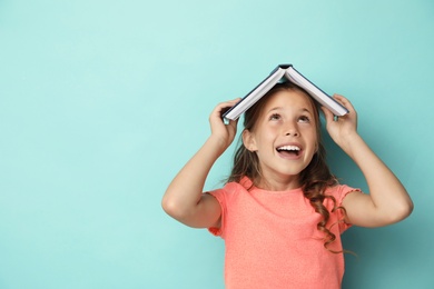 Photo of Portrait of cute girl with book on turquoise background, space for text. Reading concept