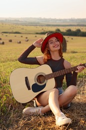 Beautiful happy hippie woman with guitar in field