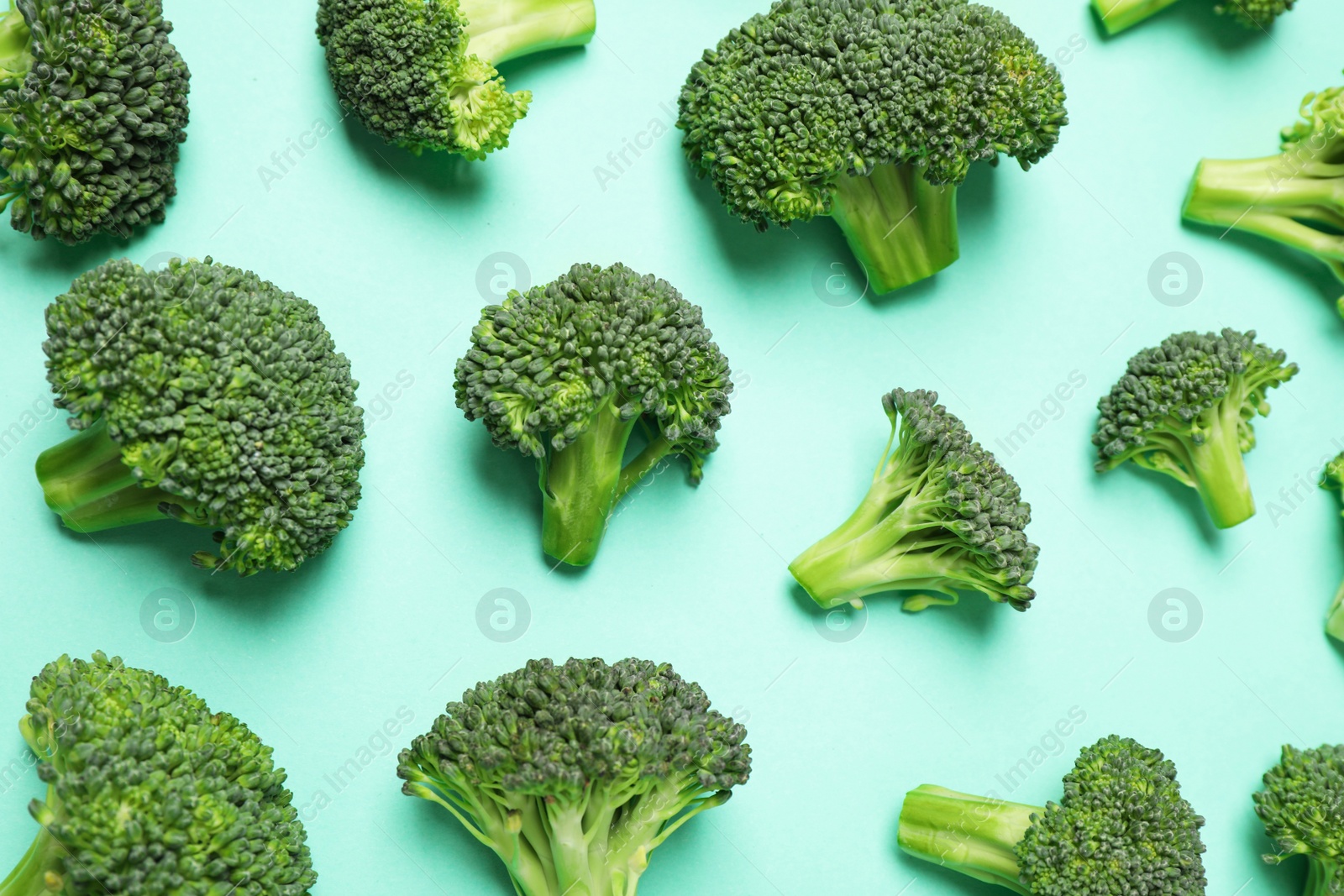 Photo of Fresh tasty broccoli on turquoise background, flat lay