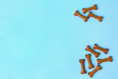 Bone shaped dog cookies on light blue background, flat lay. Space for text