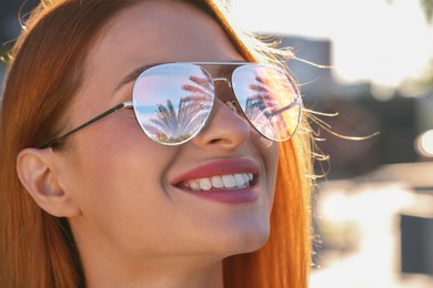 Beautiful woman in sunglasses on sunny day outdoors. Sky and palm trees reflecting in lenses