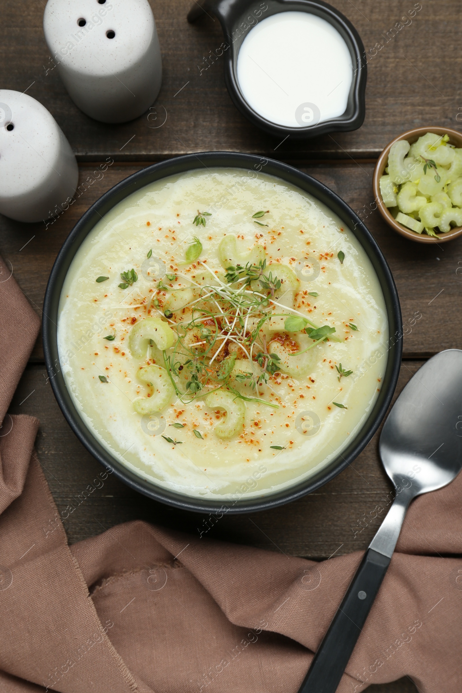 Photo of Bowl of delicious celery soup served on wooden table, flat lay