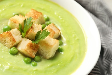 Photo of Fresh vegetable detox soup made of green peas with croutons in dish, closeup