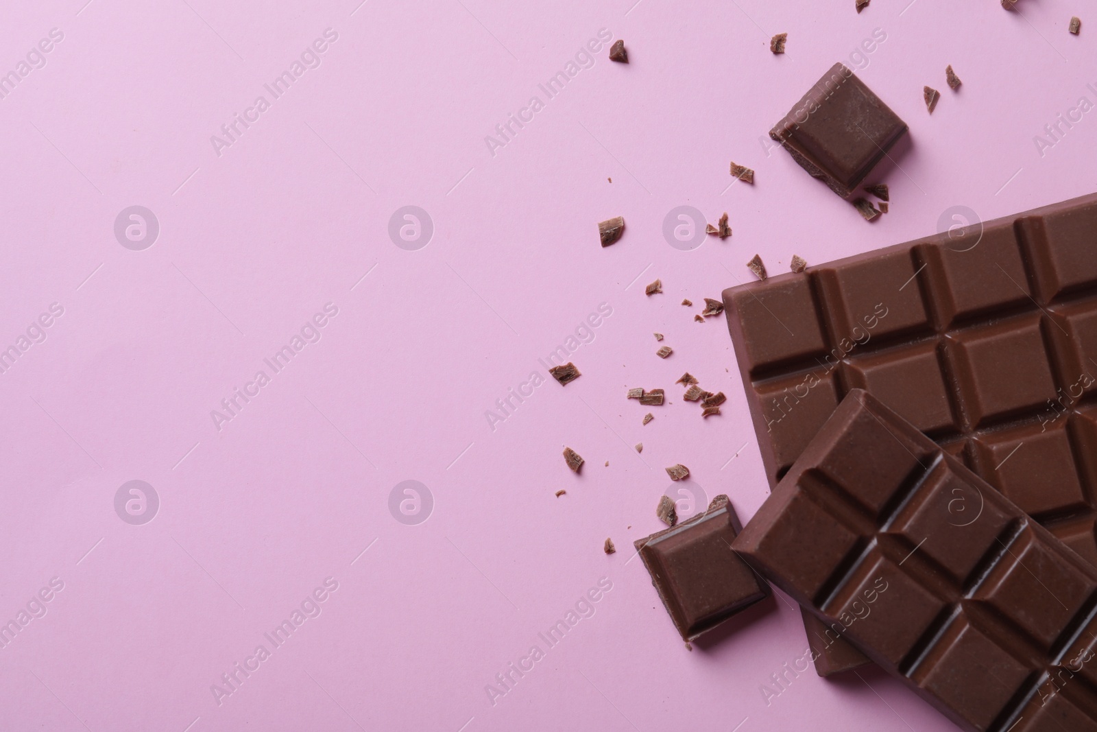 Photo of Tasty milk chocolate on pink background, flat lay. Space for text