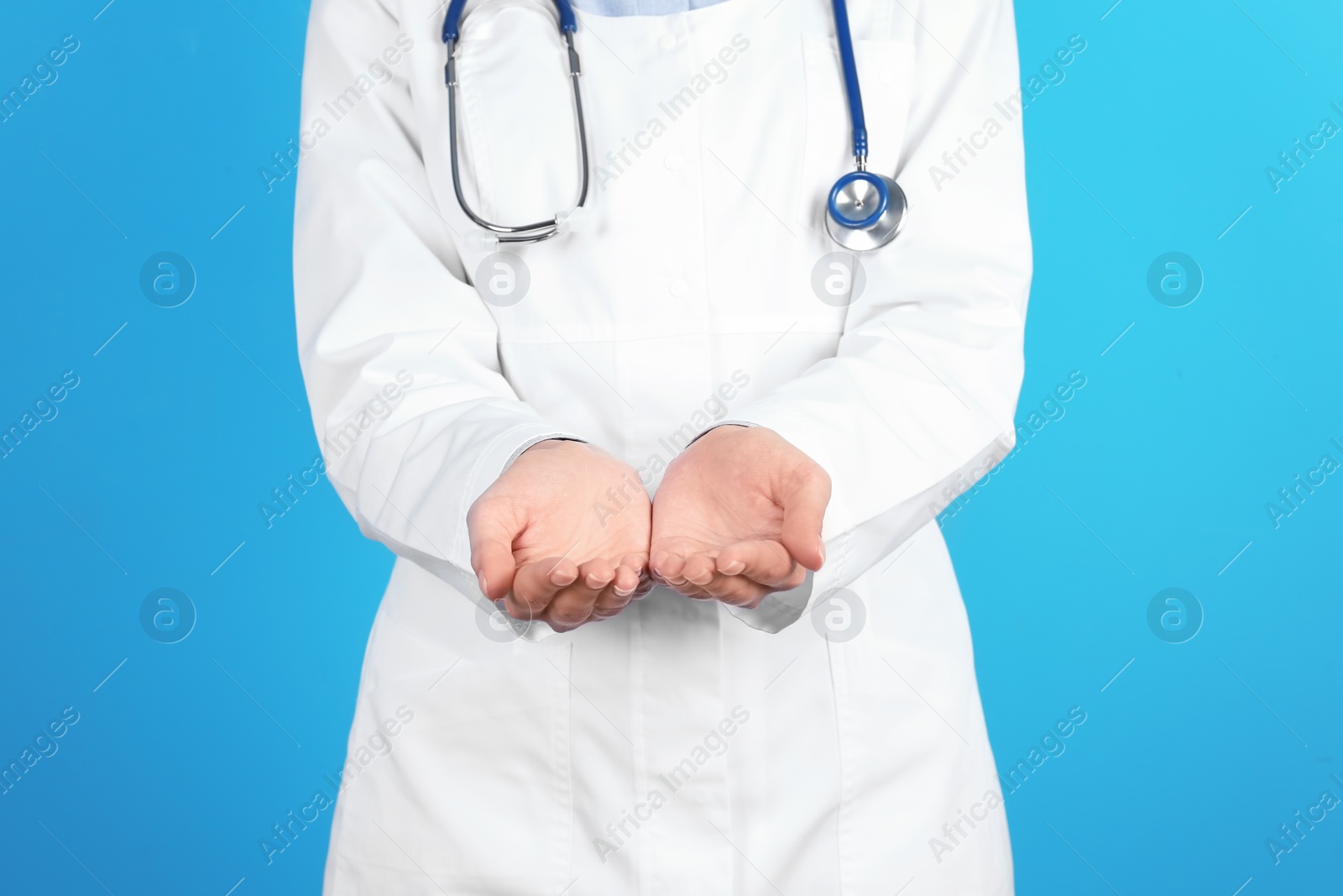 Photo of Female doctor showing open hands on color background, closeup