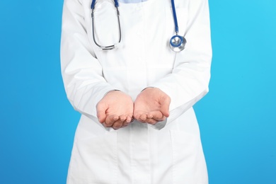 Photo of Female doctor showing open hands on color background, closeup