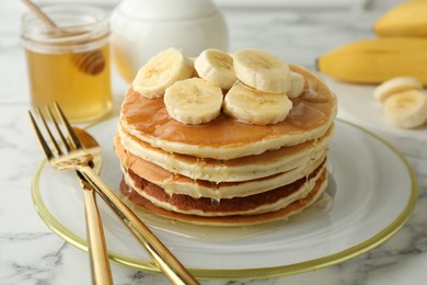 Photo of Delicious pancakes with bananas and honey on white marble table, closeup