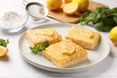 Tasty lemon bars and mint on white table, closeup